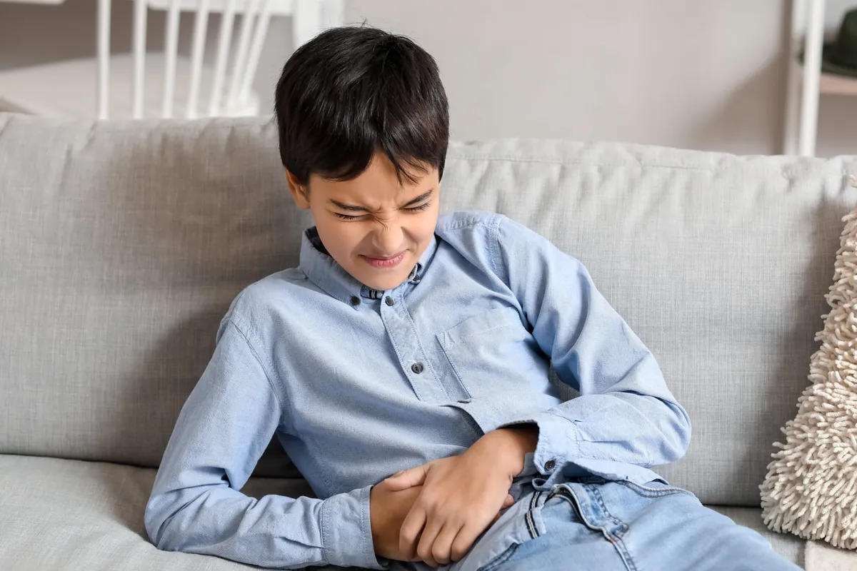 Boy on a couch holding his stomach in discomfort