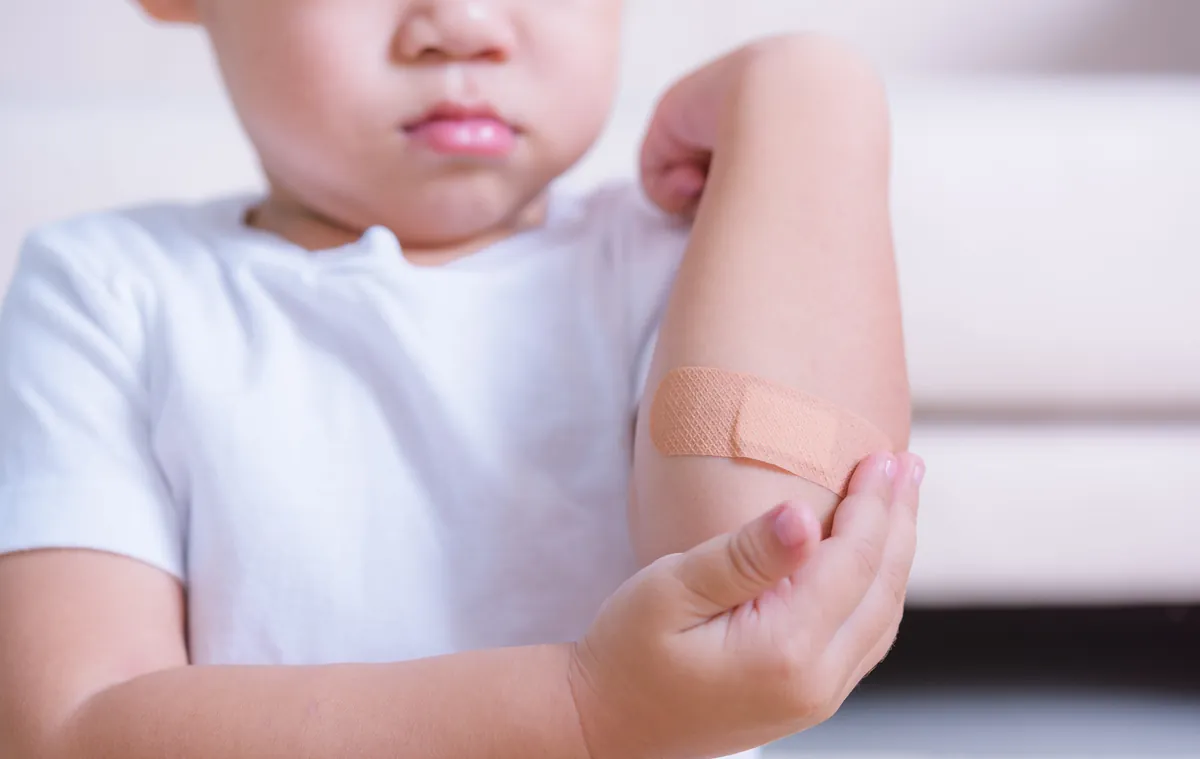 Child holding a bandaged elbow after a minor injury
