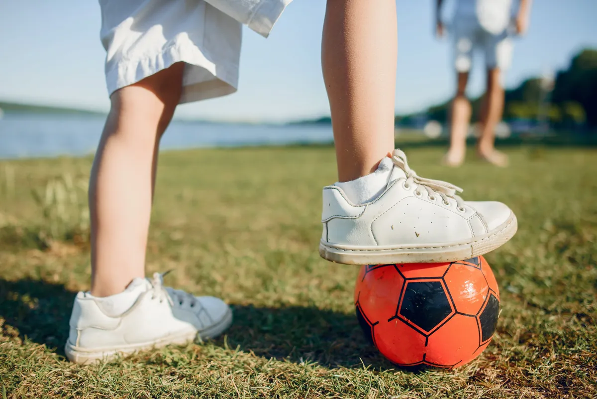 Young athlete resting one foot on a soccer ball on a grassy field