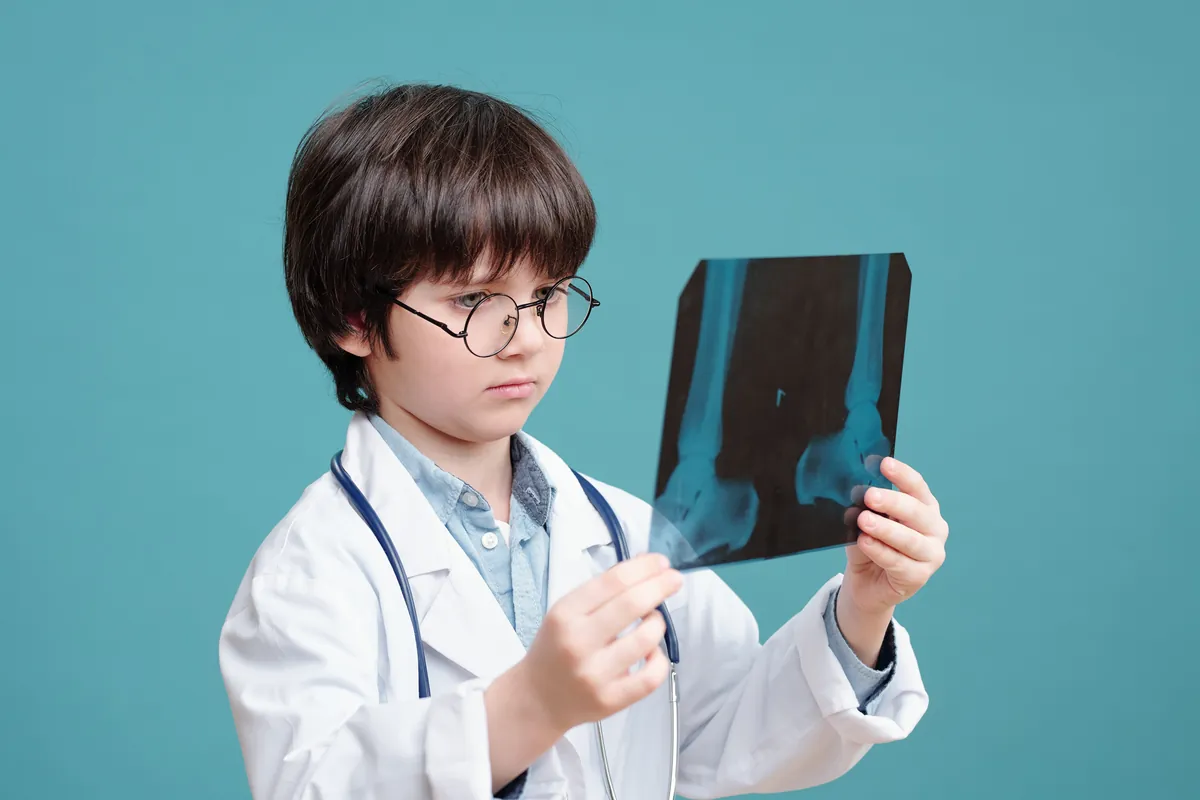Young boy in a play doctor coat studying an X-ray image